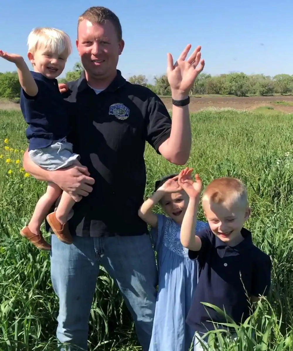 Father with 3 young kids waving in the field