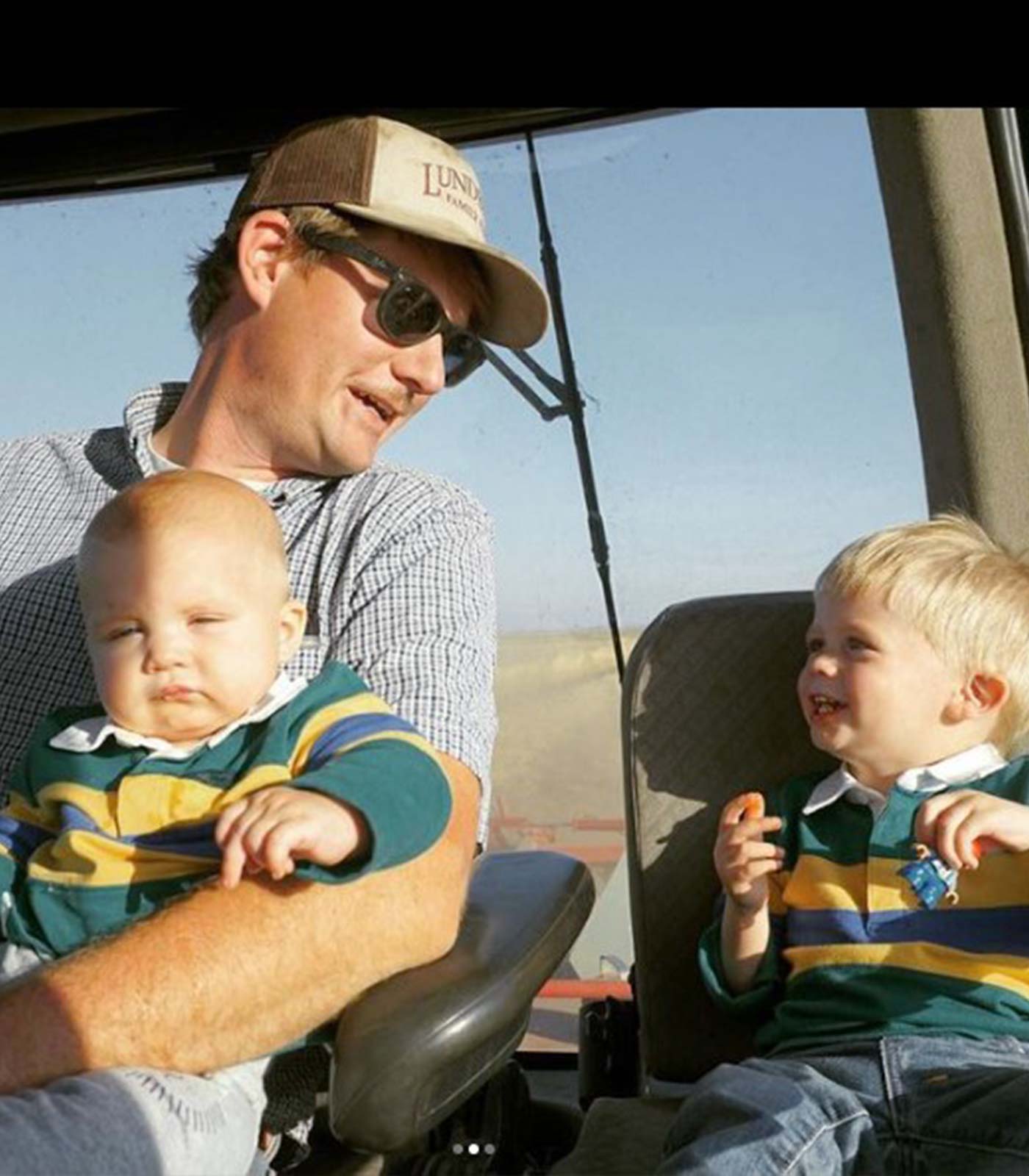 father with 2 sons riding in a tractor cabin
